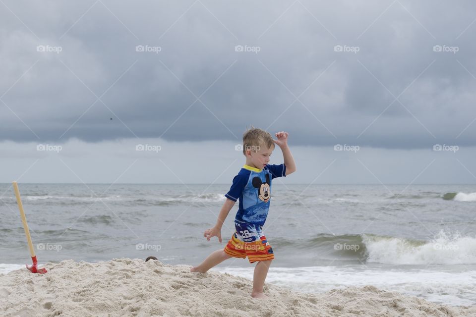 Boy walking on the beach while a storm approaches