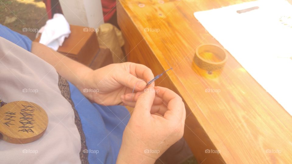 a woman making viking  jewelry with very tiny beads wrapped into the wire