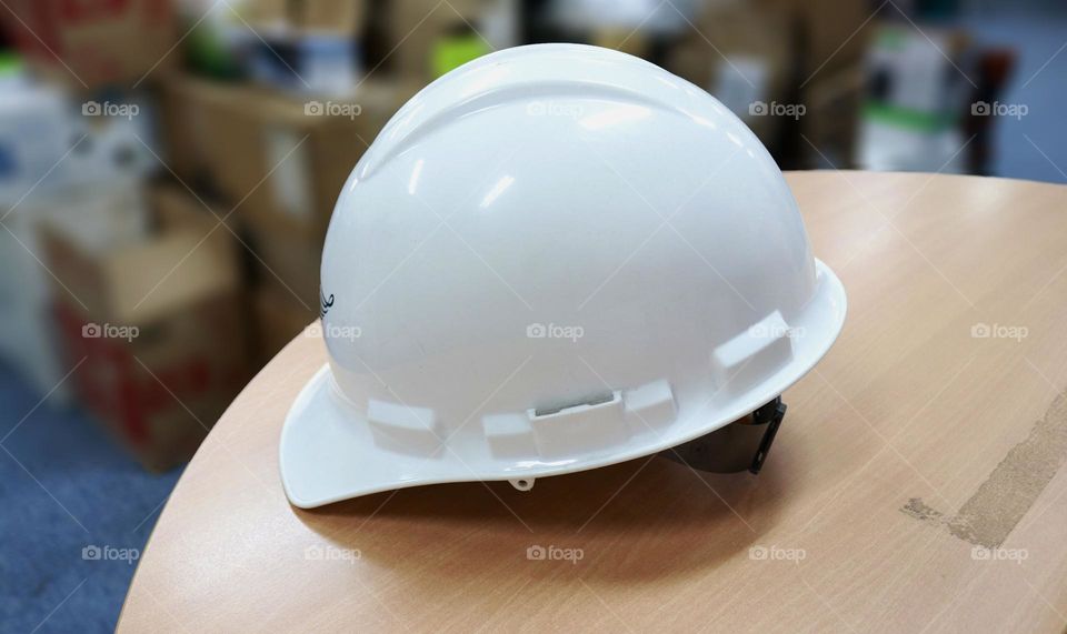 Photo of a white safety helmet on a table in a warehouse