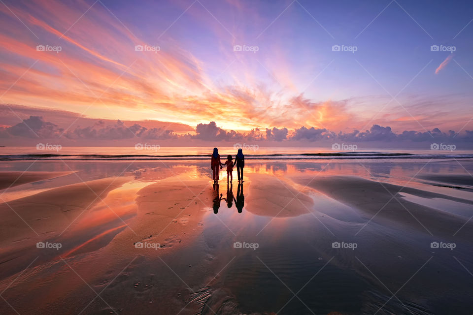 Silhouette kids reflections on the beach during sunrise