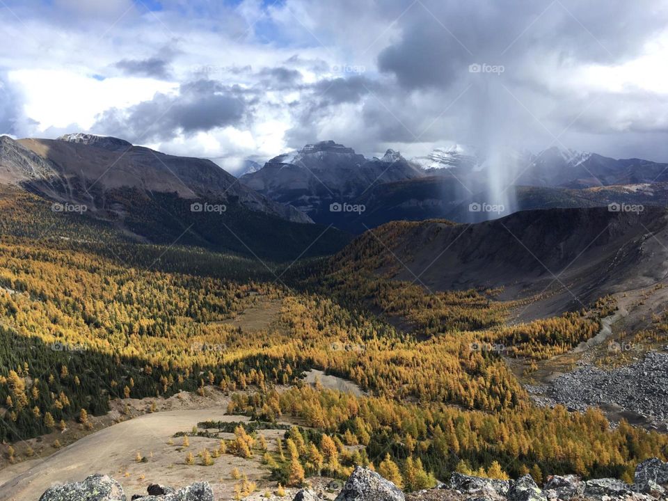 Fall storm in the mountains with the golden Larch trees in the valley.