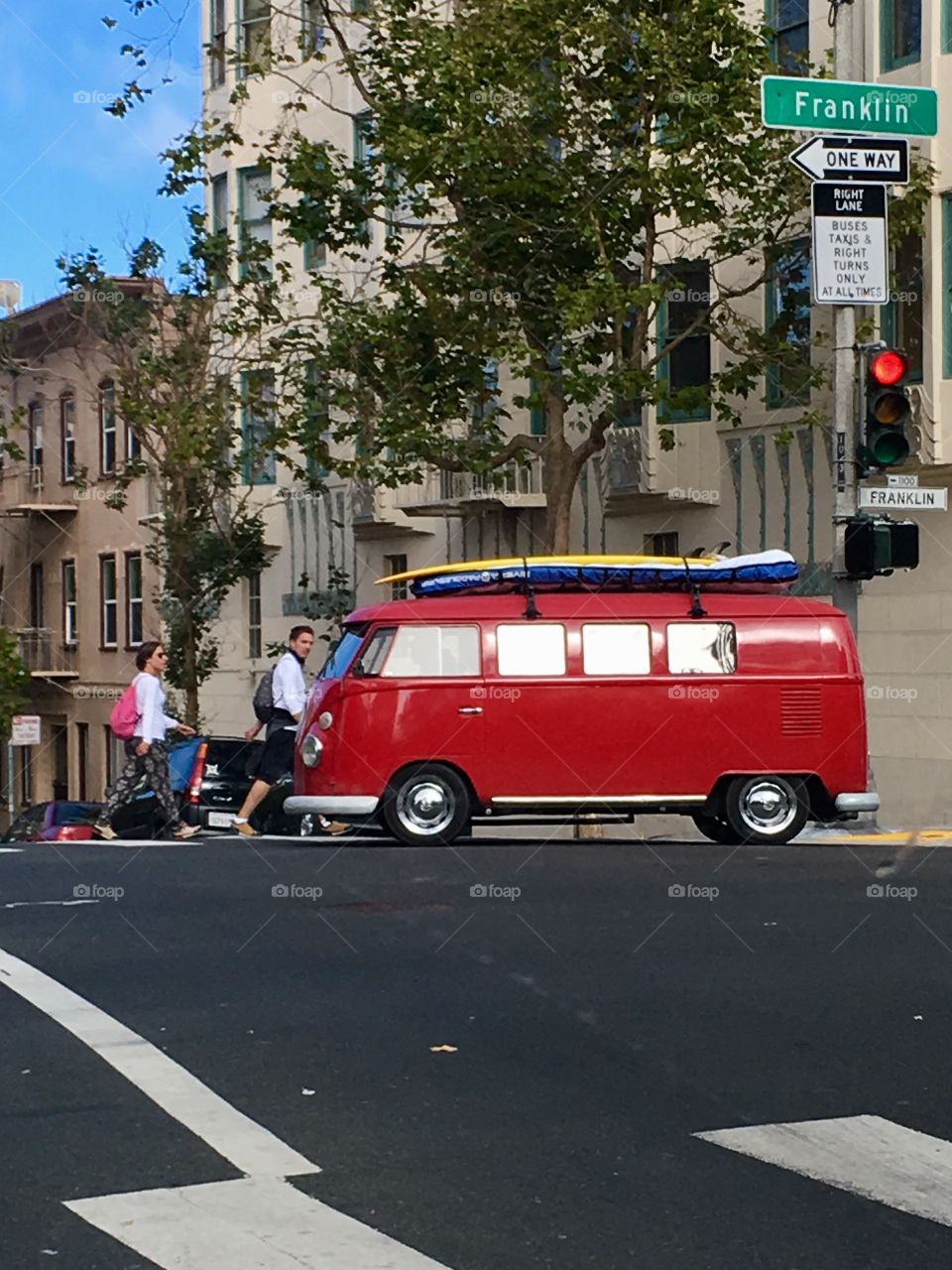 Red VW bus with a surfboard on the streets of San Francisco, CA