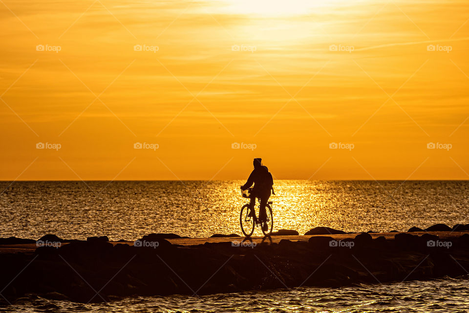 silhouette of people biking on the pier during the golden hour of sunset