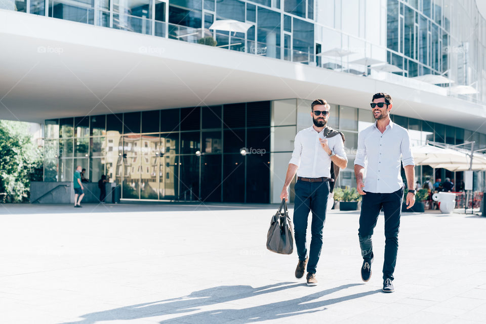 two elegant business men walking in milan business district - success, team, corporate concepts