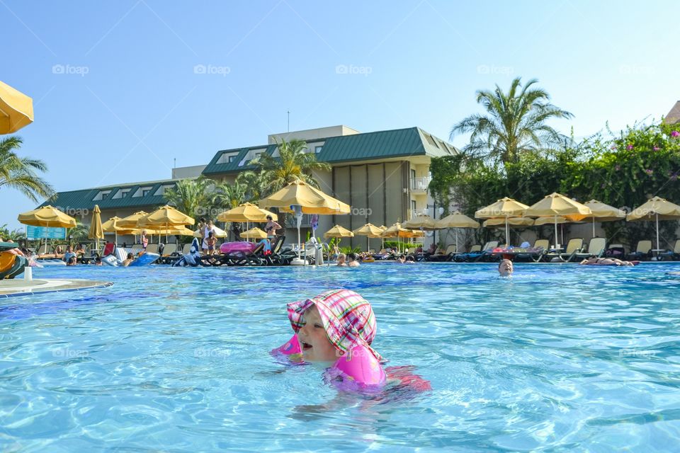 Two year old girl is playing in the pool at a resort in Turkey with her family on vacation.
