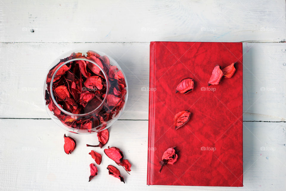 Red Book and a bowl of rose petals on white table