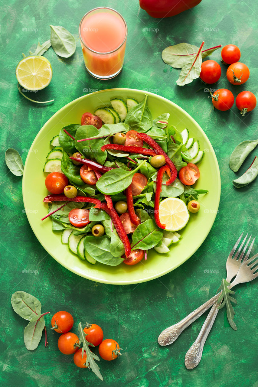 Fresh salad with spinach, pepper, olives, cucumber, tomatoes and lime