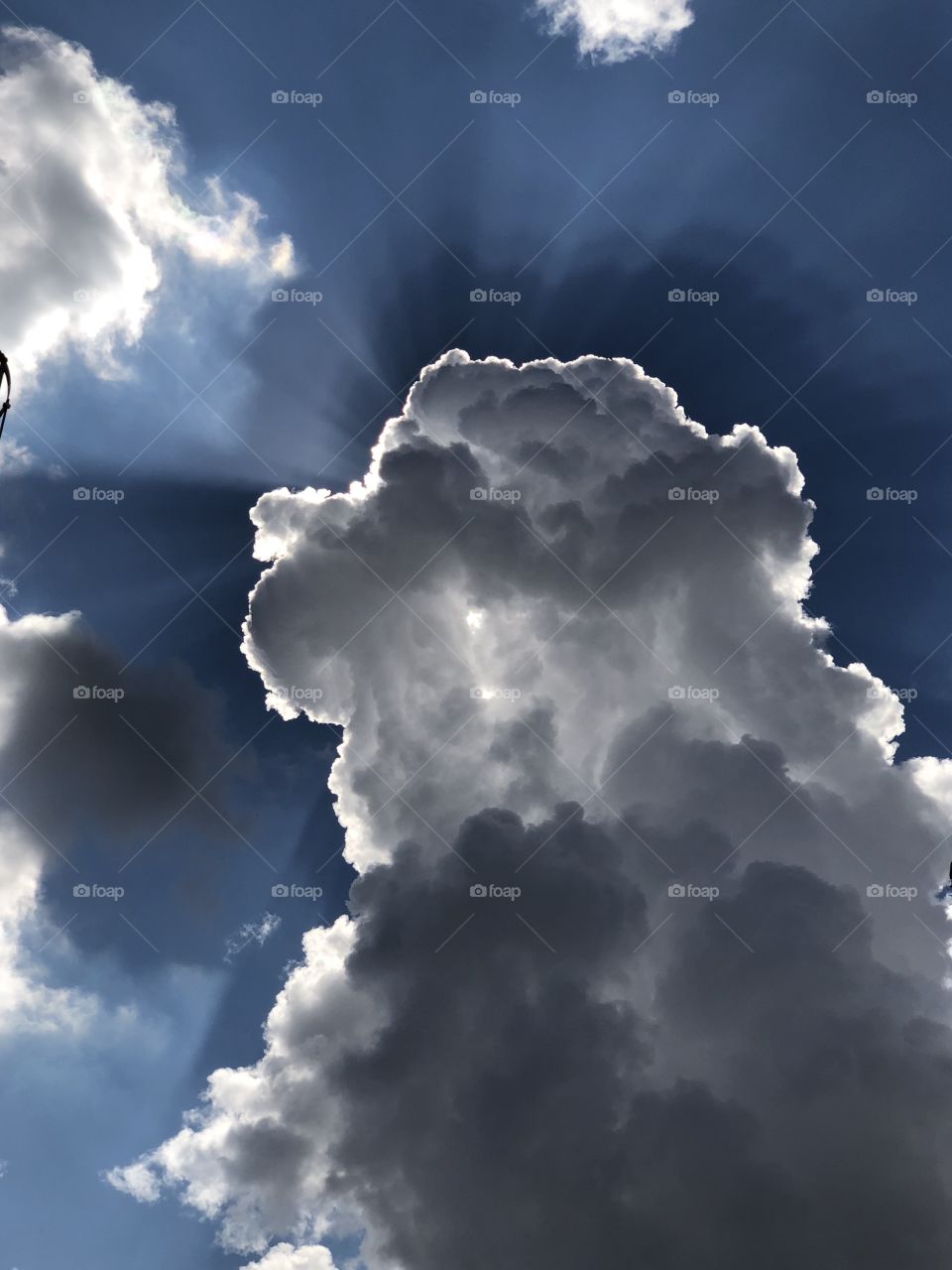 Sunrays beaming from behind building cumulonimbus clouds