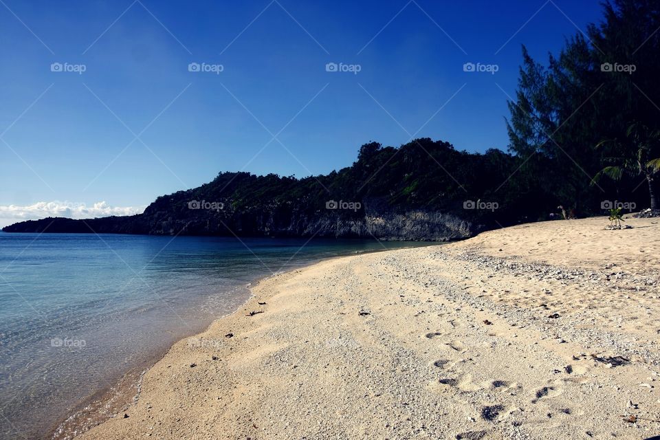 beach shore, clear sky, blue ocean and an island cove