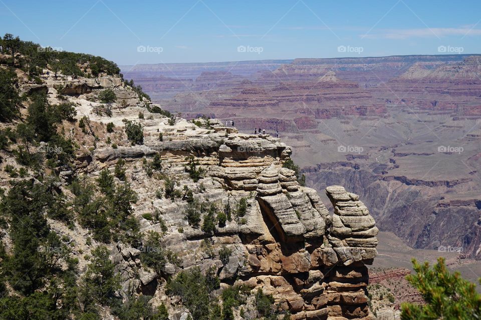 Tourists cling to a narrow rock outcropping in order to get a great view at Arizona's Grand Canyon