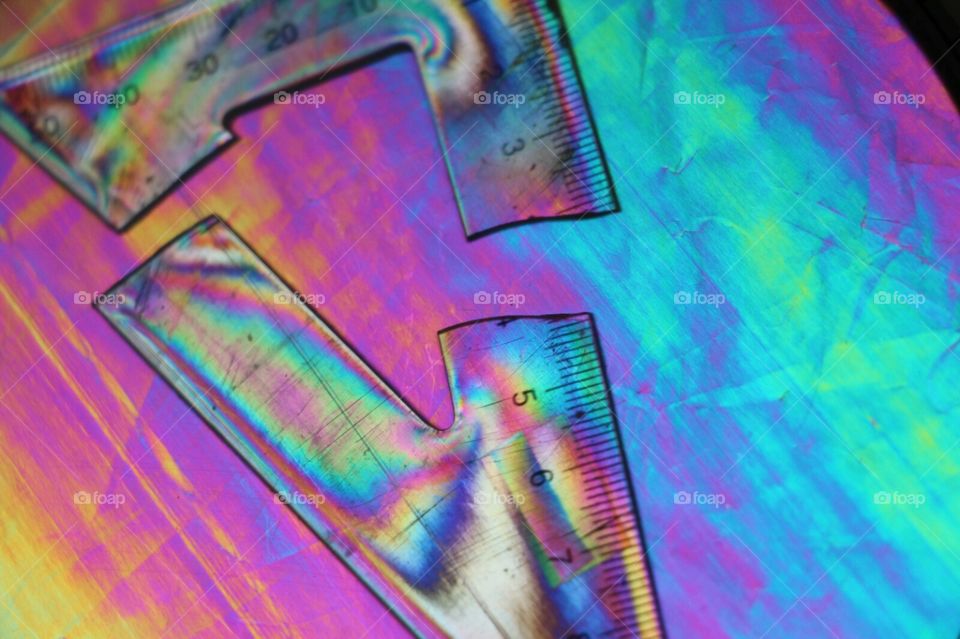 A broken ruler is placed between polarisation filters, giving it a rainbow hue.