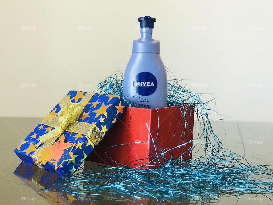 The Nivea shea smooth lotion in blue and red gift box and the box is full with blu glitter strips.