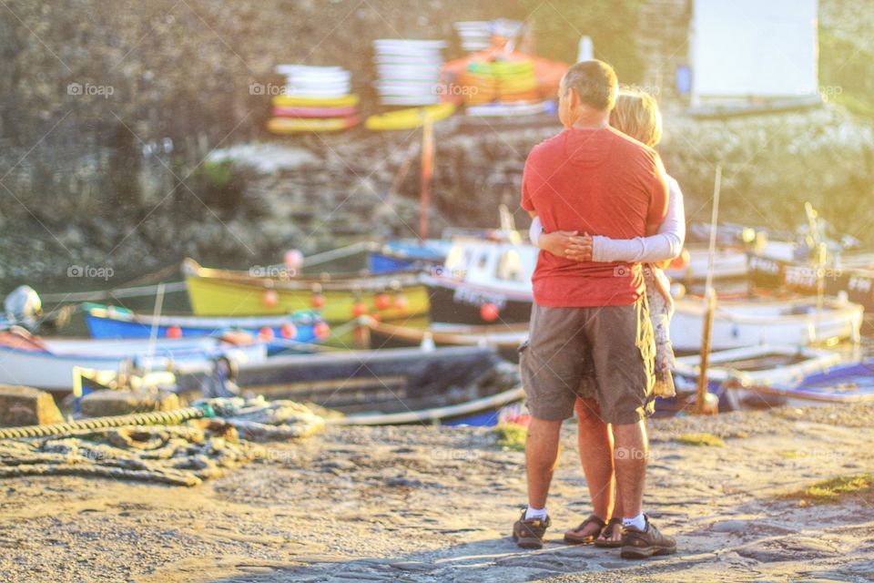 Cuddling Couple. A man and woman hug on a harbour wall whilst on holiday as the sun sets.