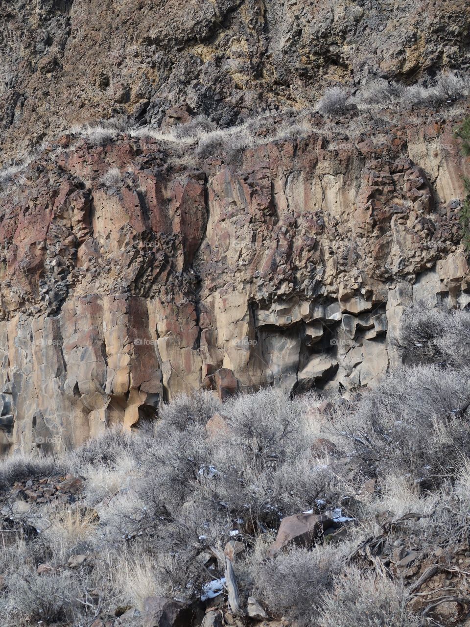 Cliffs of basalt stick out with just a bit of snow on the ground on a beautiful sunny winter day in Central Oregon. 