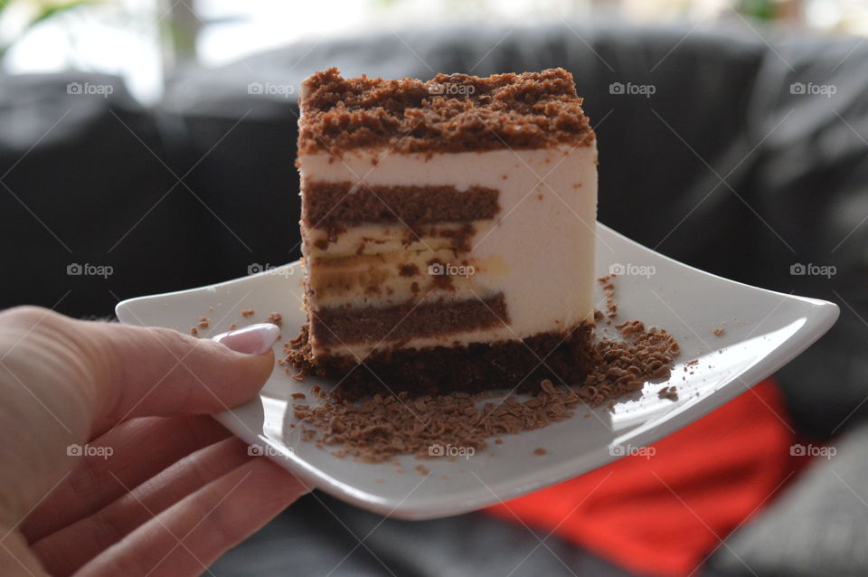 Person's hand holding cake slice in plate