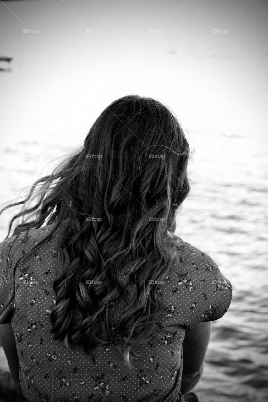 Girl sitting by a lake, edited in black and white. 