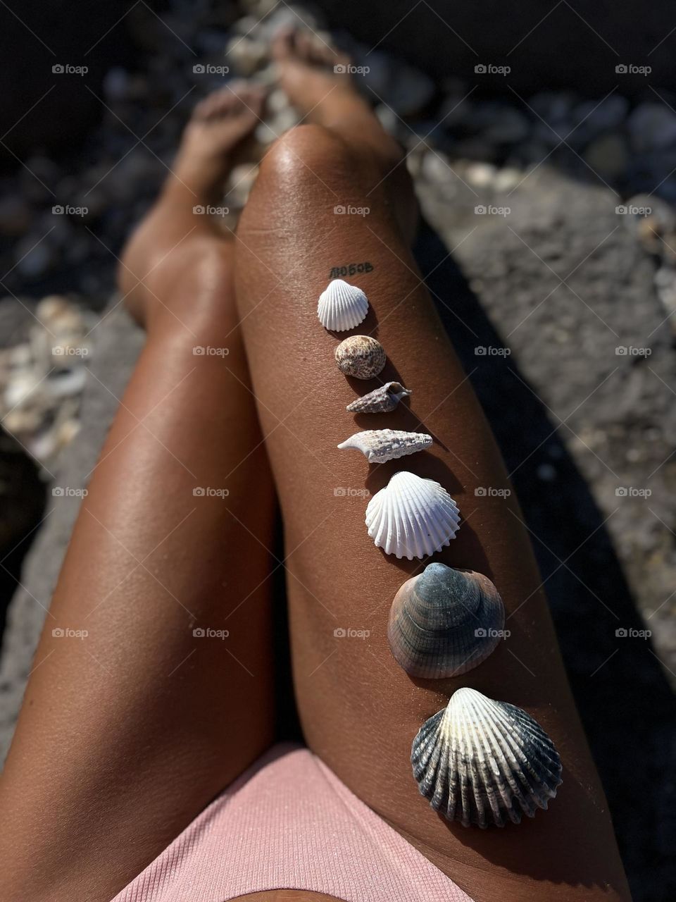 Beautiful shells on the womans leg, beautiful summer photo, interesting journay 