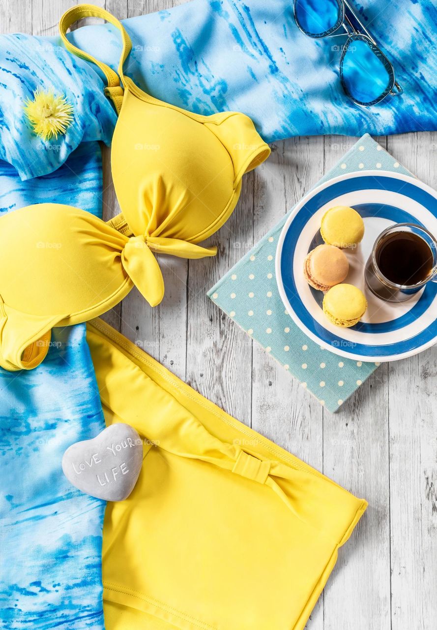 Blue & yellow swimwear flat lay with coffee & macaroons 