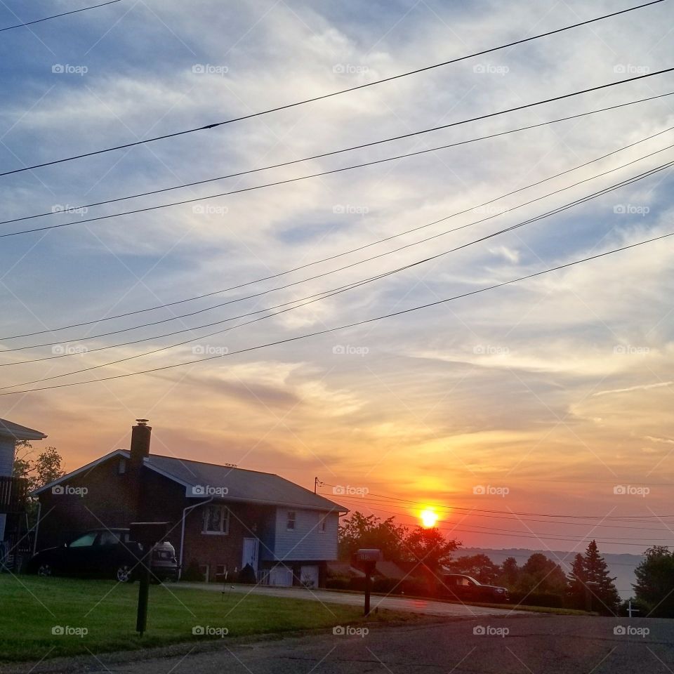 House in foreground with beautiful orange and gold sunset in background fading into a blue sky with soft clouds
