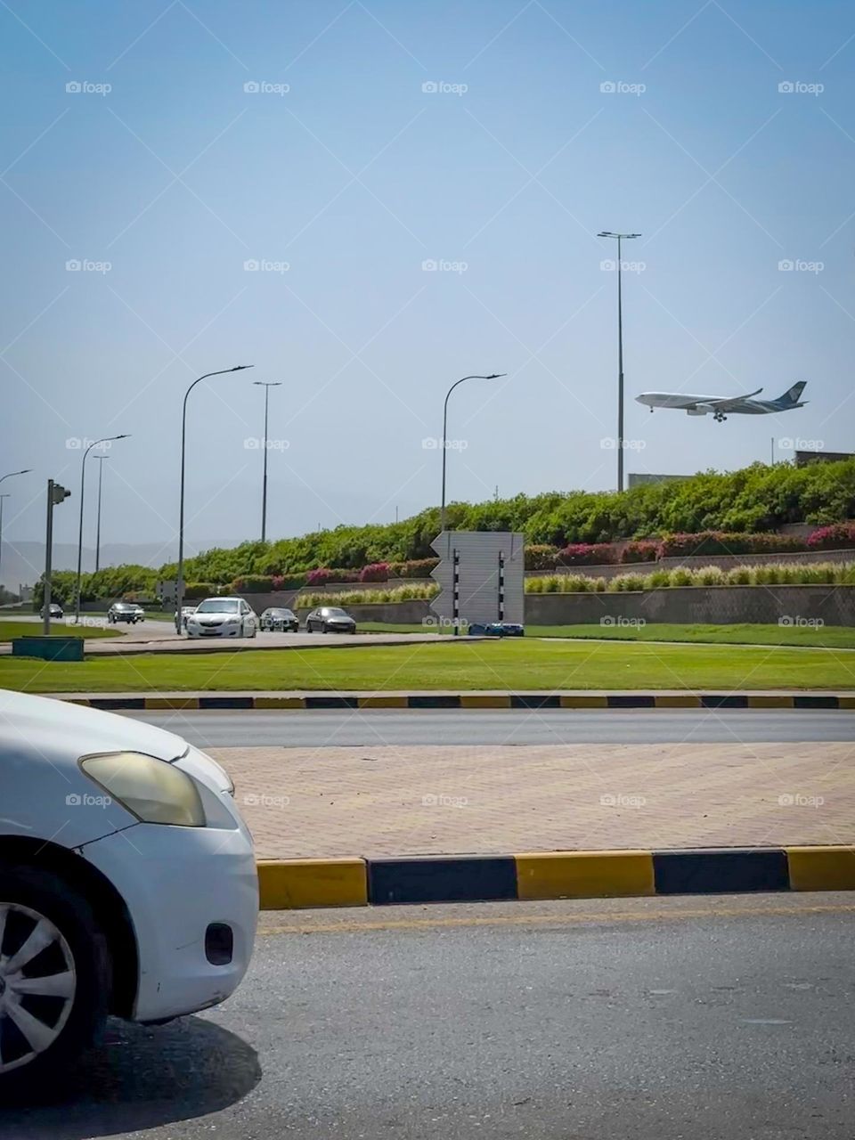 A commercial passenger airplane seen during its final approach over a highway with cars. 