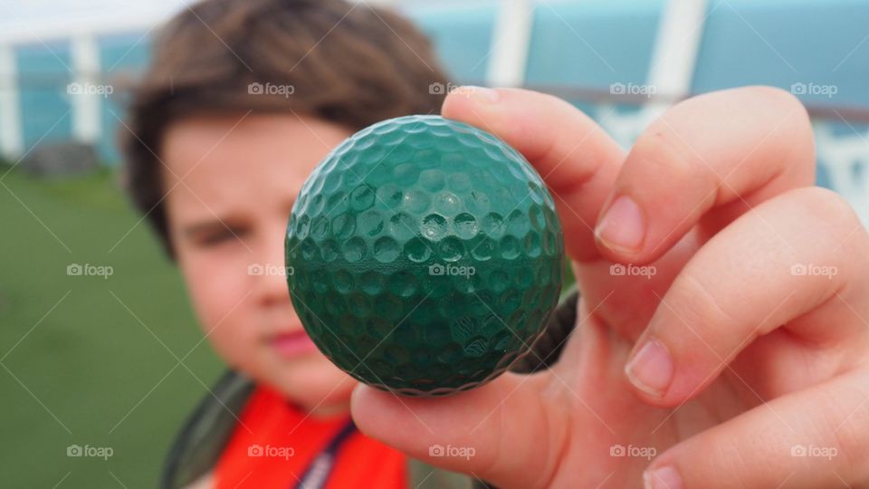 Young kid showing a golf ball