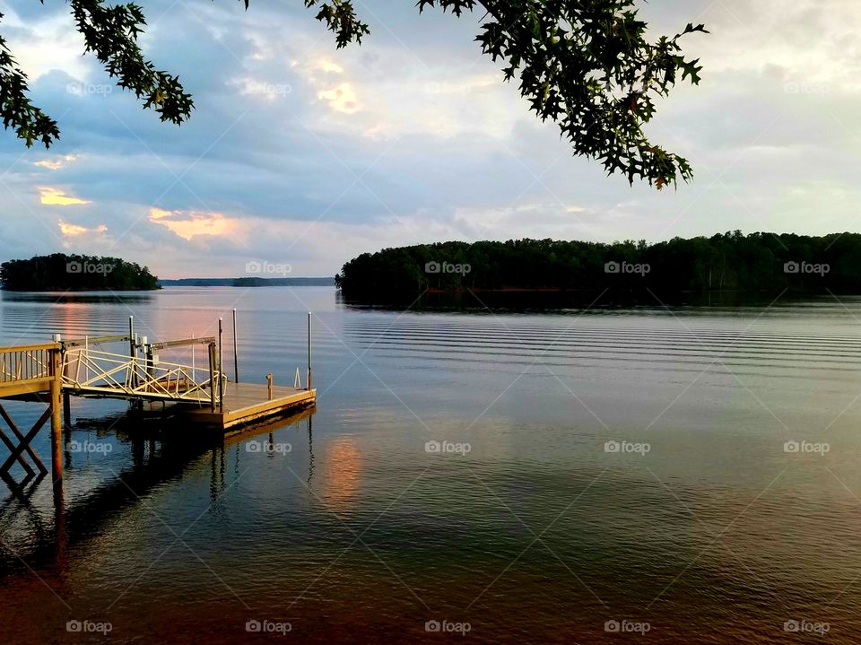 dock view as sunset reflecting on lake.