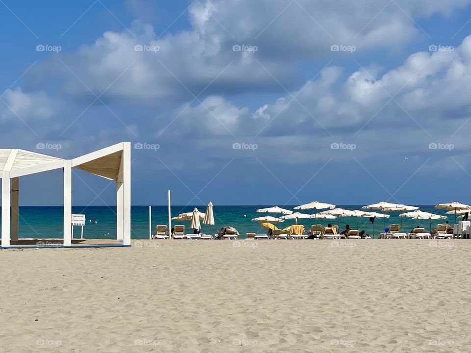 Sea beach landscape with blue sky and white umbrellas 