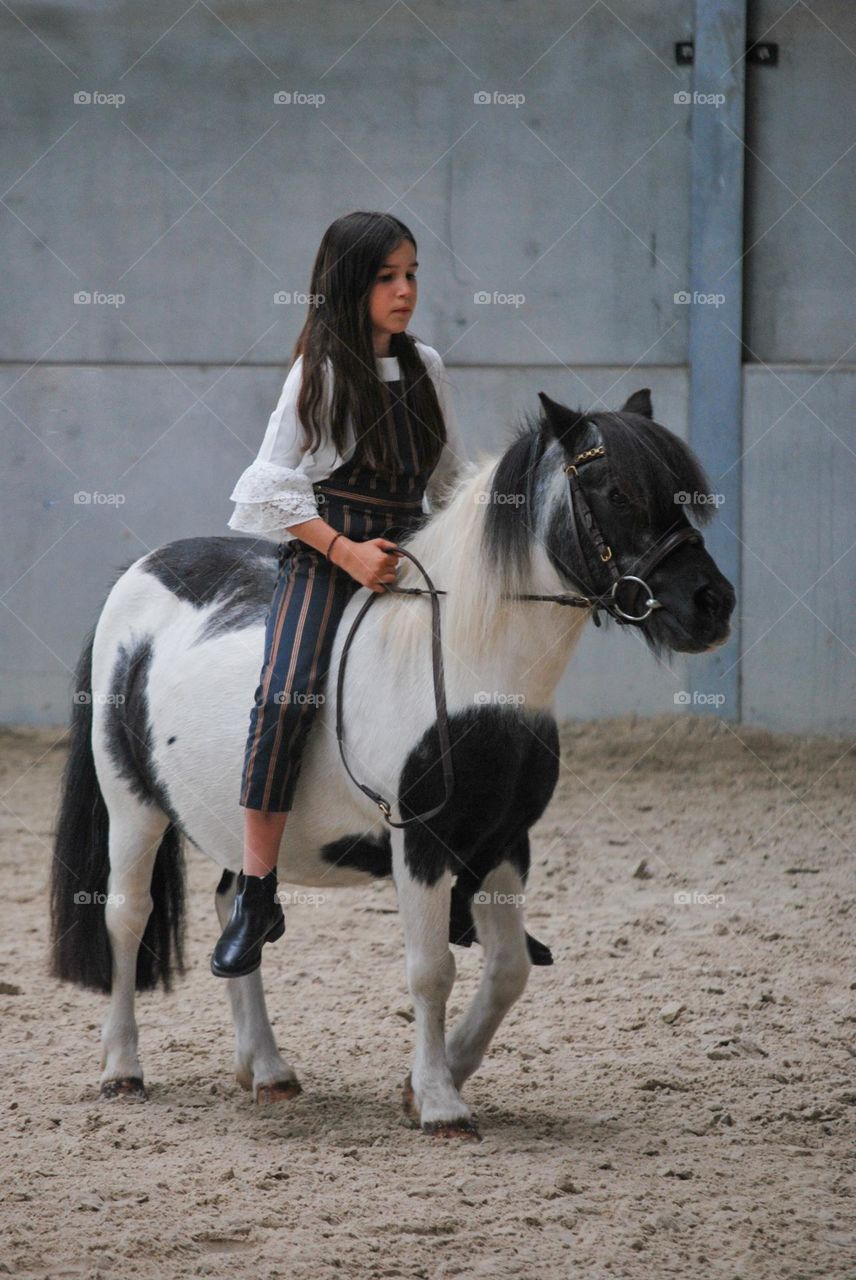 Teenage girl riding her horse / pony in a stable