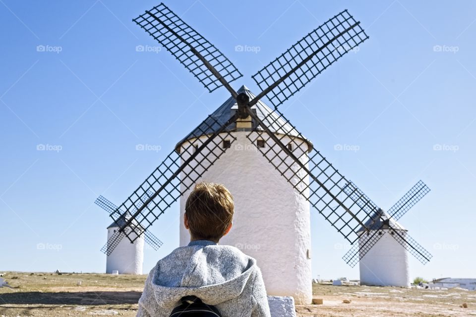 Woman contemplating old windmills in Spain 