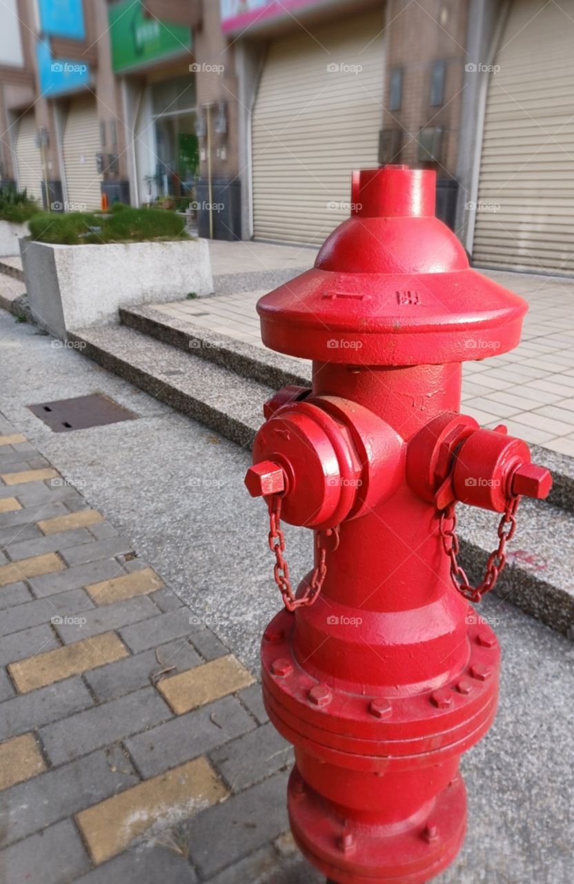 Red fire hydrant situated on the sidewalk.