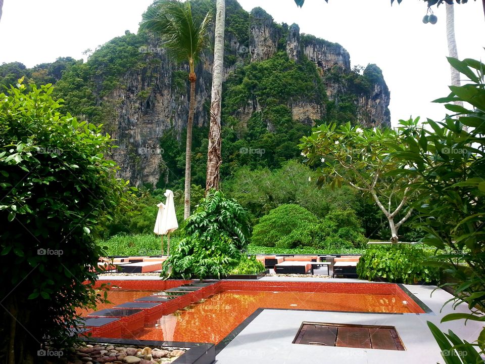 swimming pool in tropical setting by rock cliff, Thailand