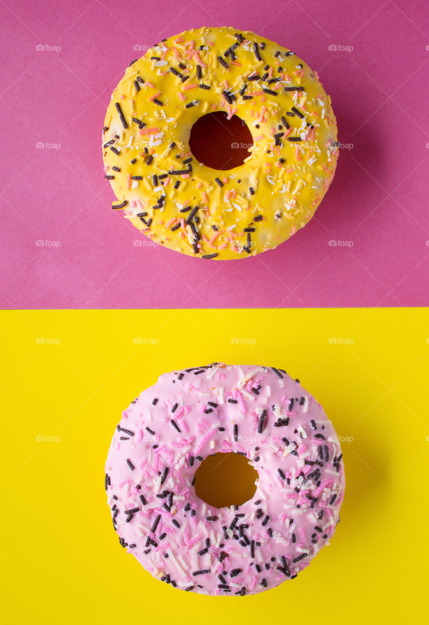 Tasty pink and yellow donuts on colourful background in pop art style