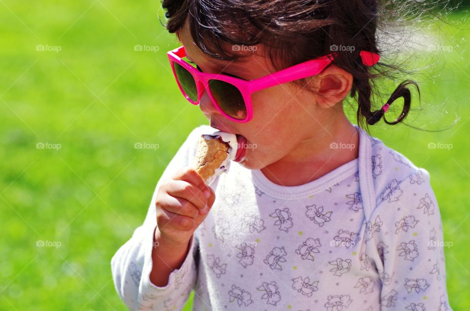 The small kid eating ice cream at the summer time.