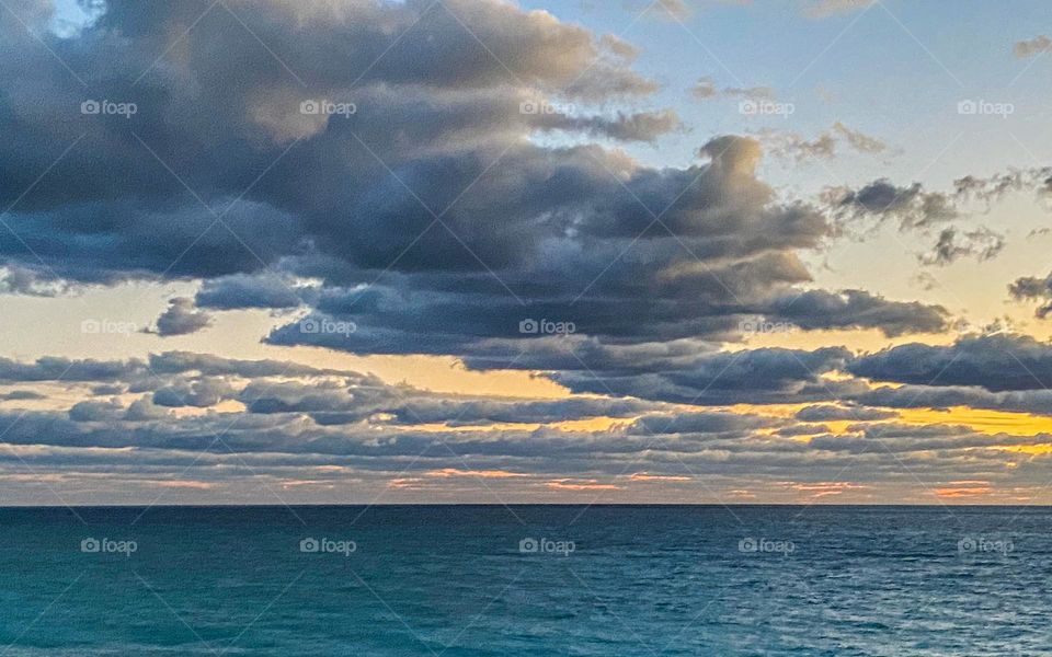 Clouds mission - sunrise over the ocean along the Florida coast.  Turquoise water with big clouds overhead and the sun just peeking through. 