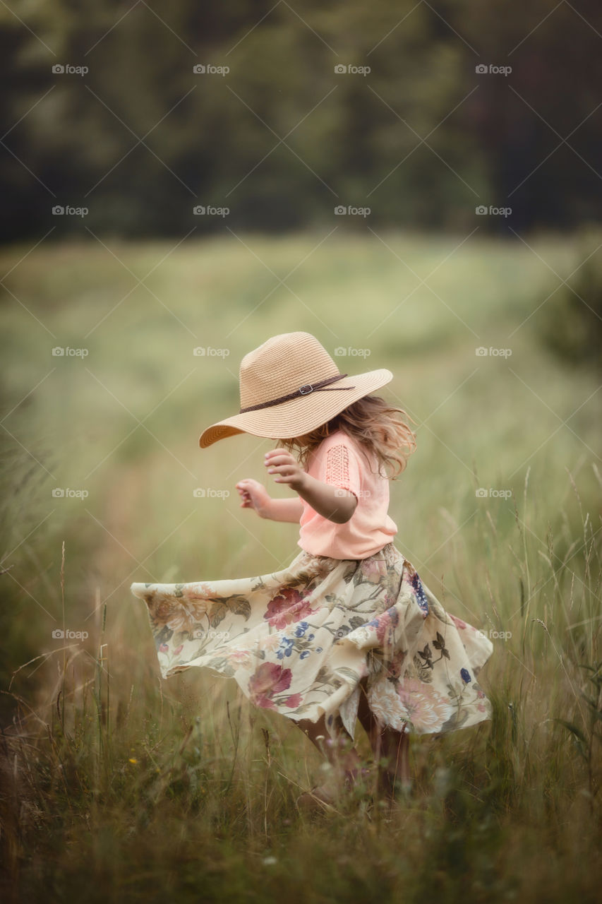 Little girl with a hat in a meadow