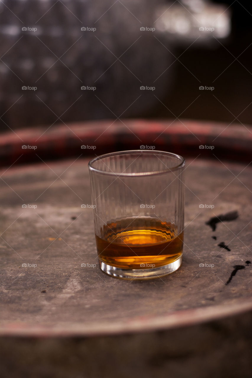 beautiful shot of whiskey. whiskey in the glass on wooden barrel