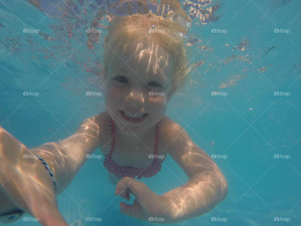 Little girl of four years old diving underwater to play at Alcudia Pins on Majorca.