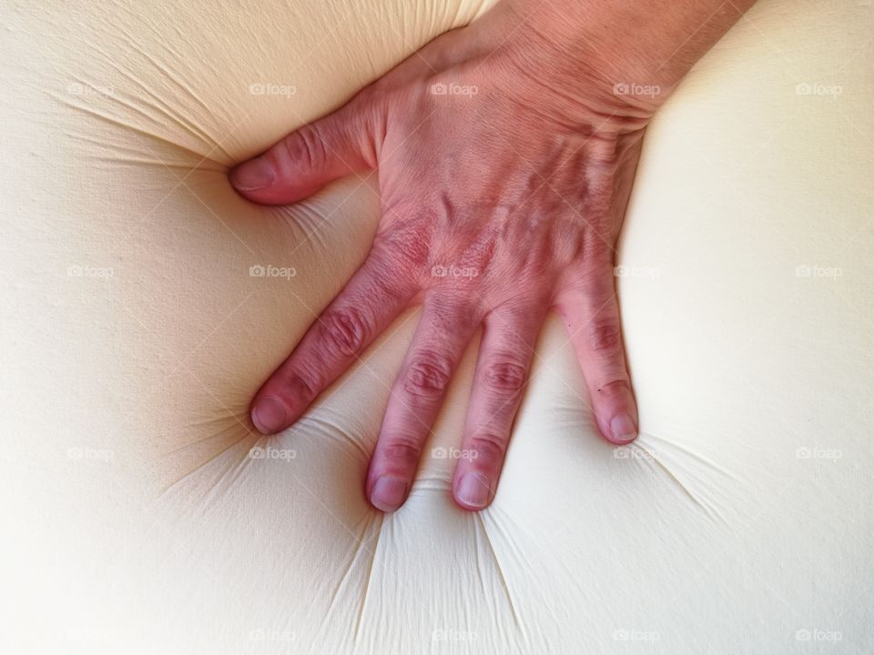 Hand presses a soft pillow in memory foam