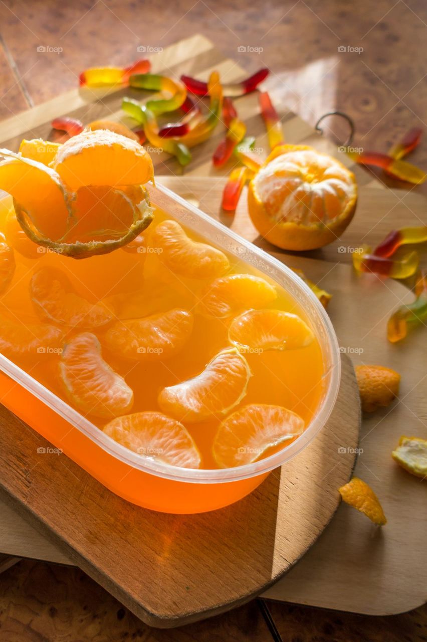 Delicious orange jelly with tangerine slices in a container and jelly worms.