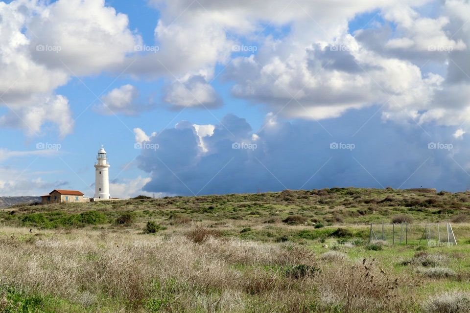 Lighthouse on the hill with cloudy sky 