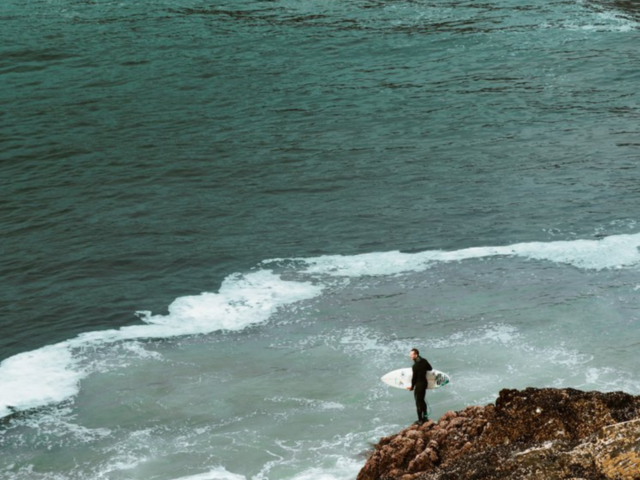Surfer By Rocks