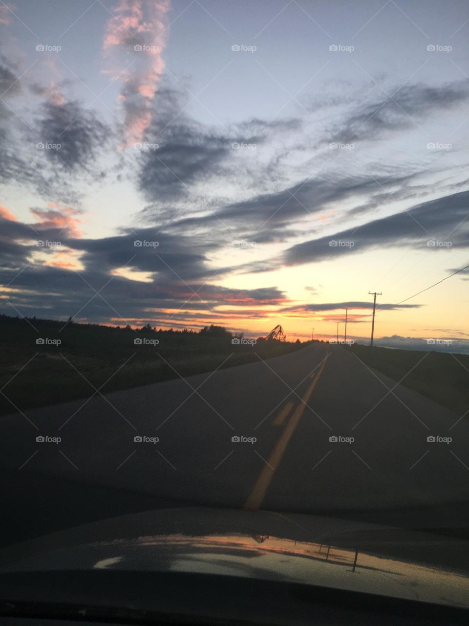Driving into the sunset with dark clouds ahead. Summer evening in Maine.