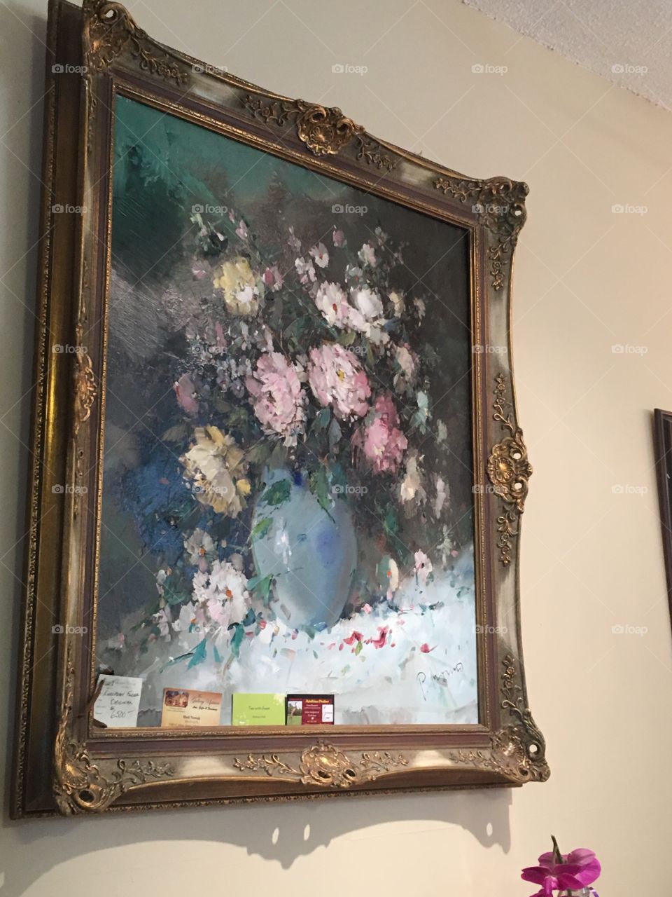 A floral painting on sale located in a tea house.