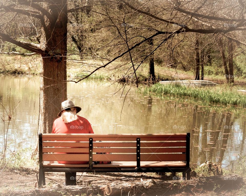 Vintage style photo of a person sitting on a bench next to a lake