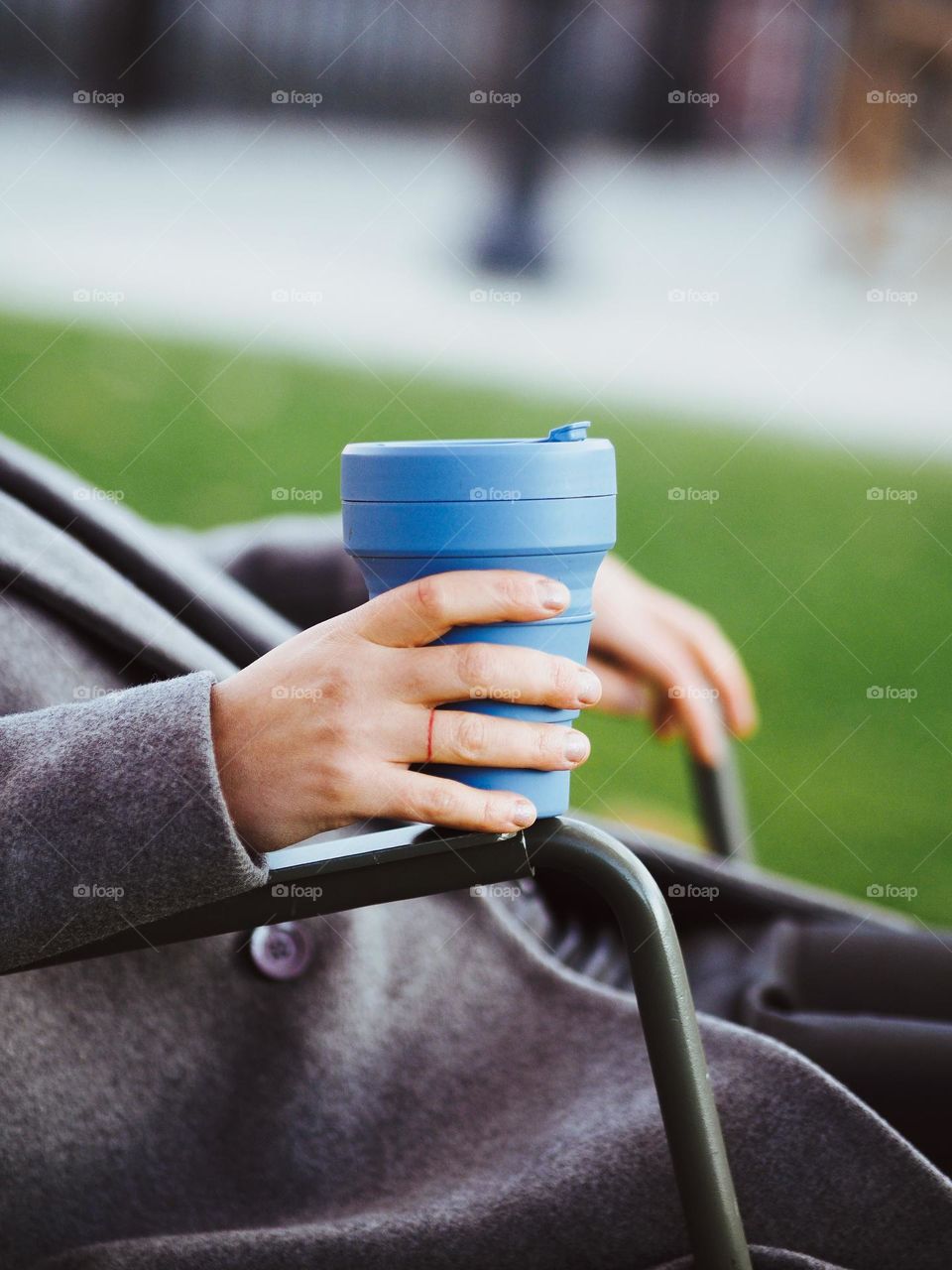 Close-up of a woman's hand holding a reusable blue coffee cup