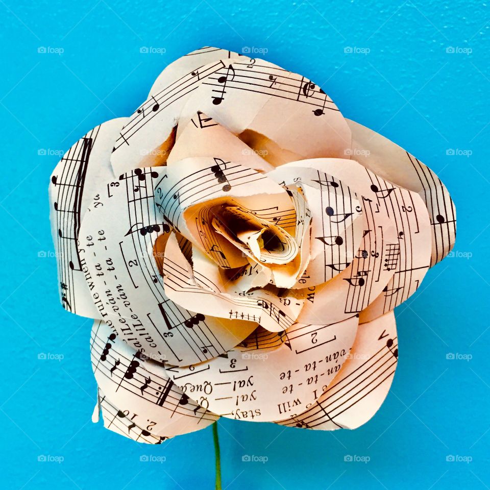 Black and white flower made of sheet music paper on a vibrant blue background 