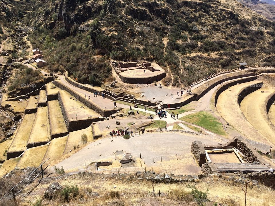 An aerial view shows tourists exploring an Incan ruin in the Sacred Valley of Peru. 