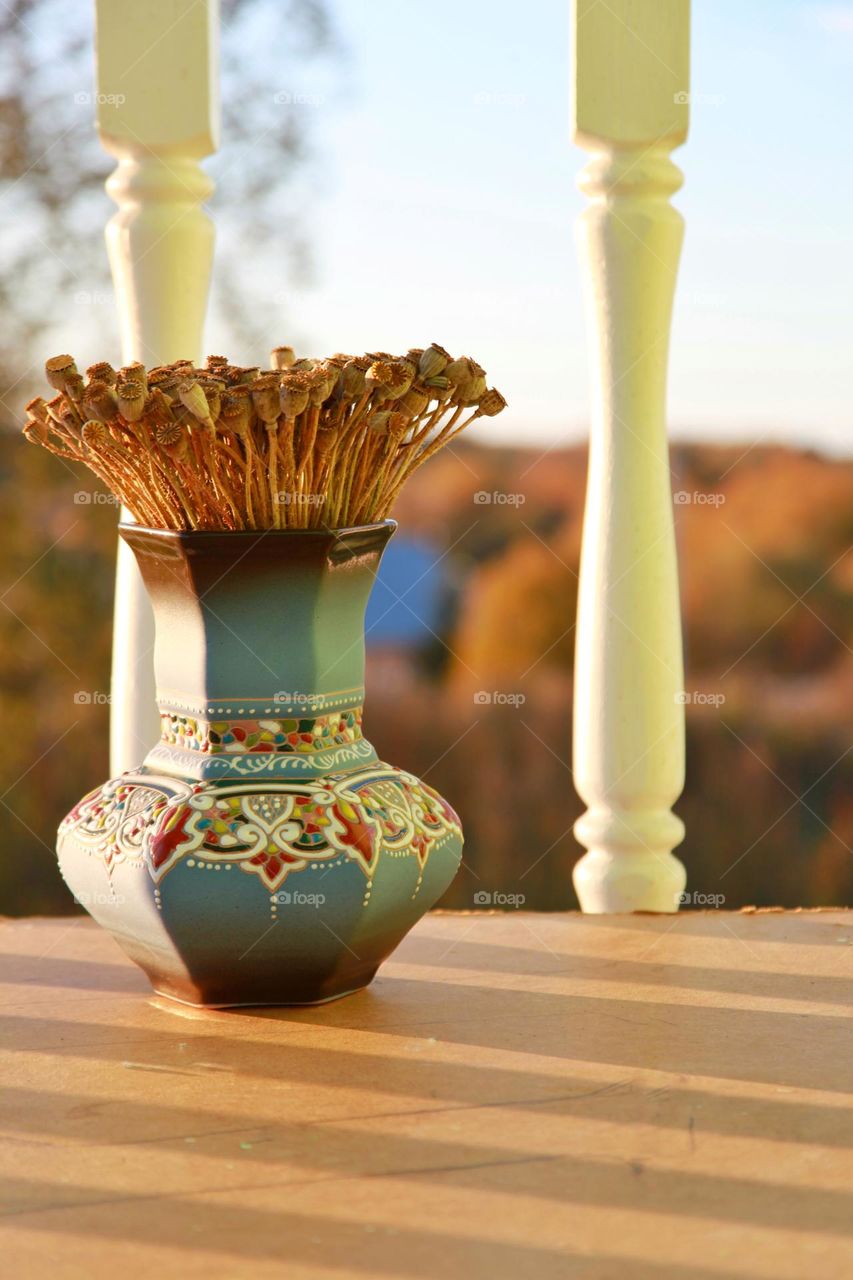 evening still life of a vase of flowers on the balcony near the railing, with an autumn forest in the background