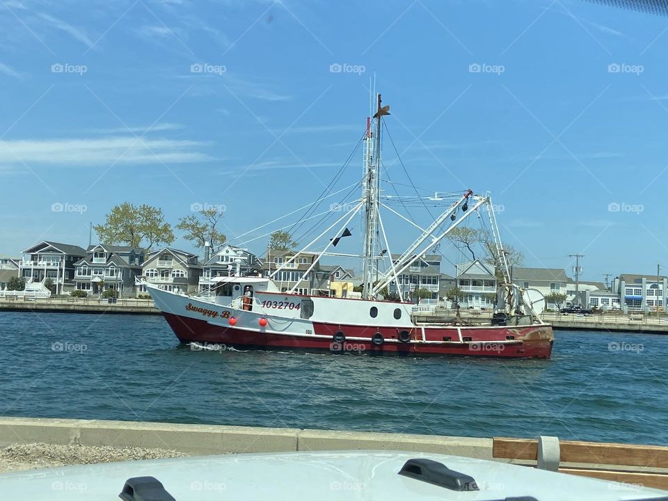 A red and white fishing boat named Swaggy B on the waters of the Manasquan Inlet taken from the inlet parking lot in Point Pleasant Beach, NJ while sitting in my Jeep enjoying the view.