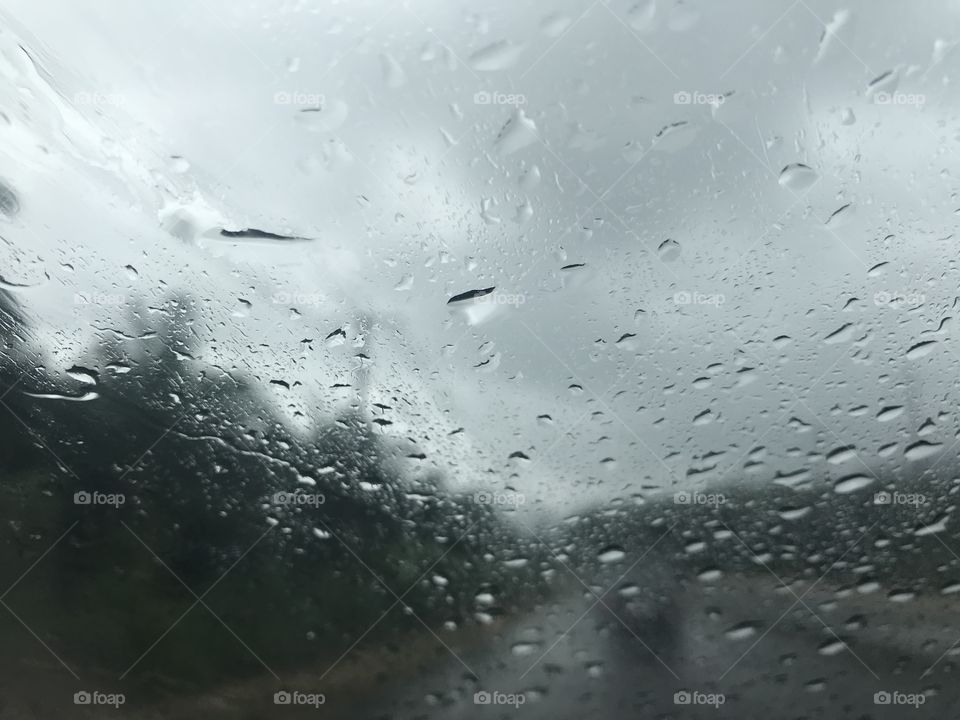 blurred road scene from car front windshield with full of raindrop and hardly see one car in the front when raining and storm
